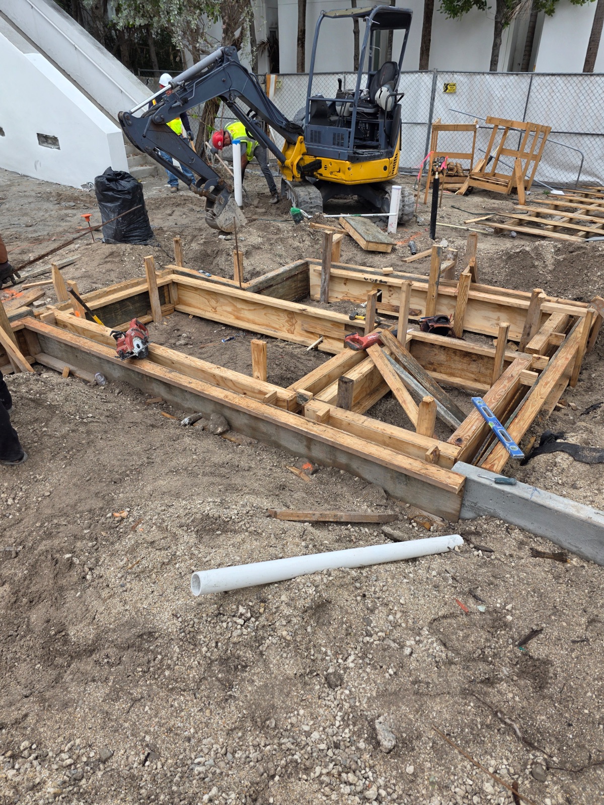 Foundation formwork with mini-excavator and crew